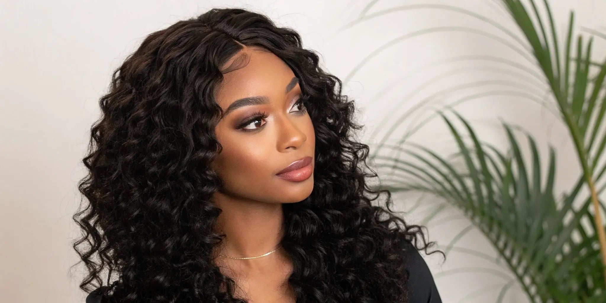 Woman smiling while wearing a curly closure wig with a natural-looking hairline.