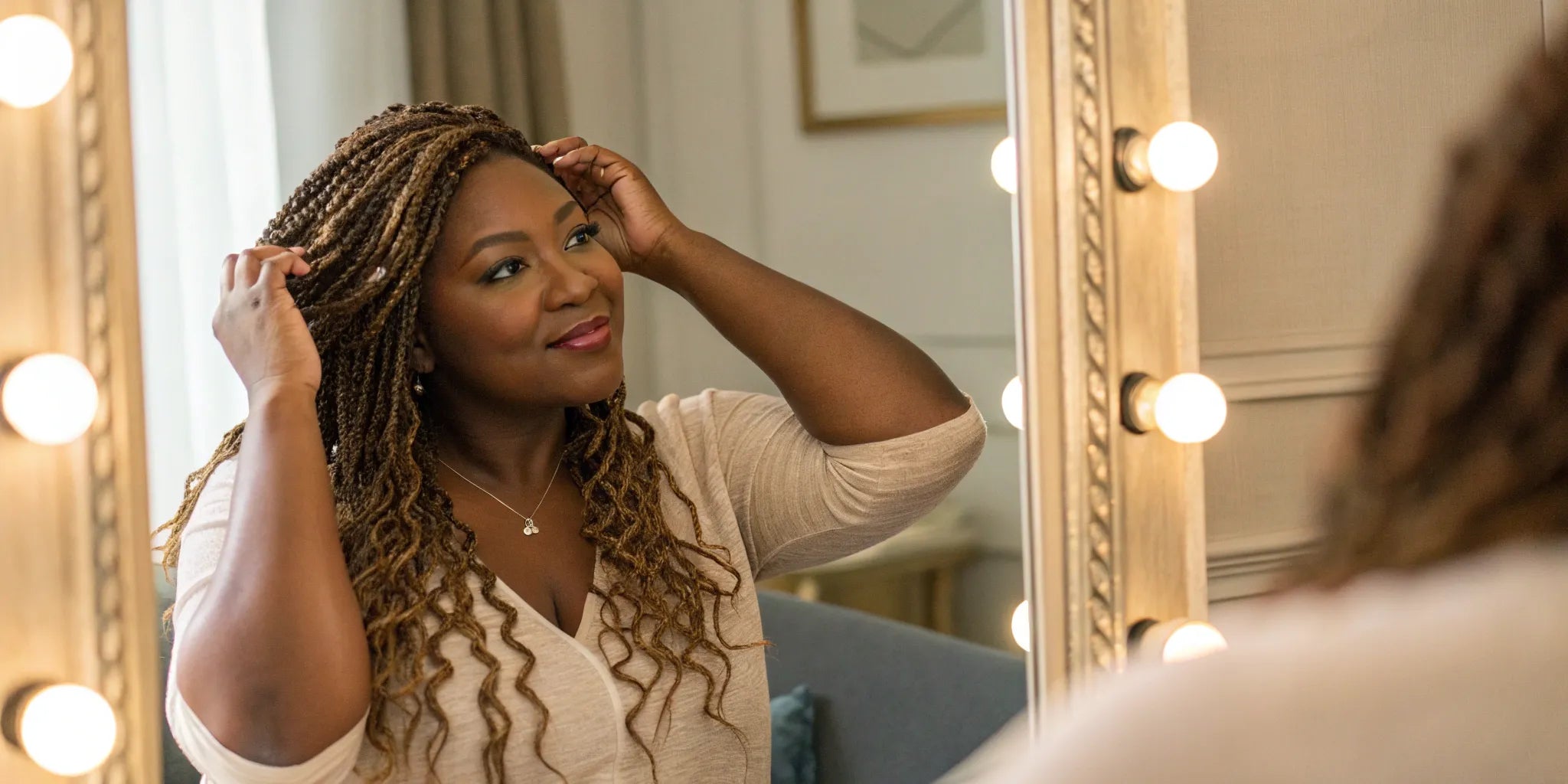 An African American woman styling her long, braided wig.