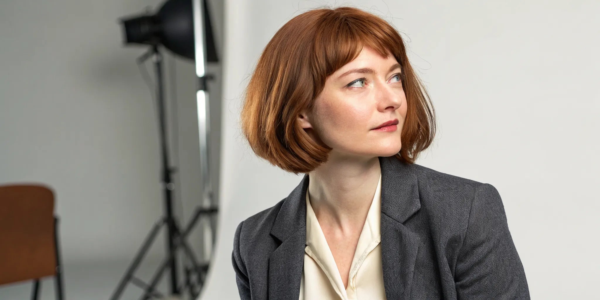 A woman wearing a short, stylish auburn wig in a bob cut.
